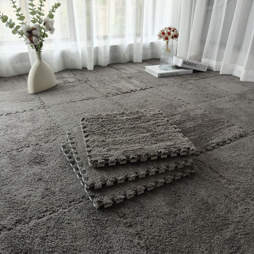 Stack of grey CloudSoft solid foam floor tiles on a grey rug, showing the interlocking edge.