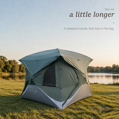 HarperShelter semi-automatic camping tent in sage green pitched on a grassy lakeside bank at dusk, fly open over the mesh door, with calm water and treeline behind.
