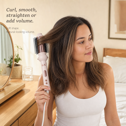 StyleOrbit hair styler in pink with the round brush head, held in a model's hair in a bright bedroom while styling.