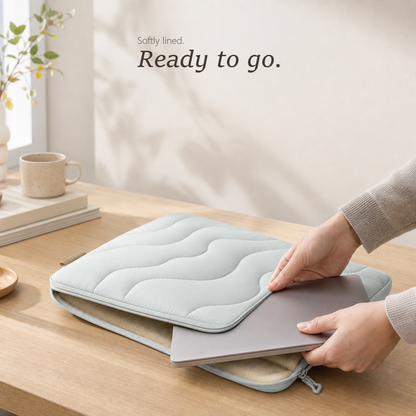 TerraSleeve laptop sleeve in cloud mist, lying open as a hand slides a 14-inch silver laptop into the soft beige fleece lining.