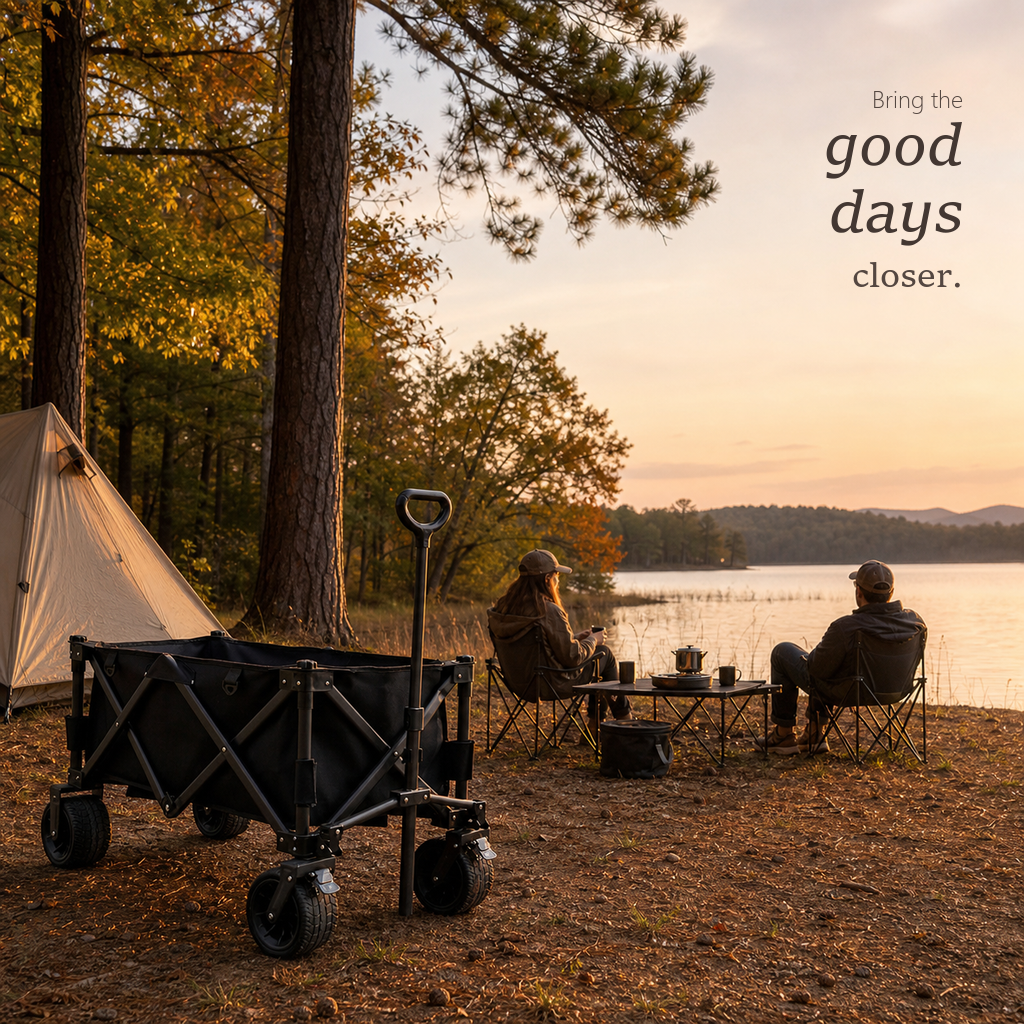 TrailFold wagon in black parked by a lakeside tent while two campers relax in chairs at sunset.