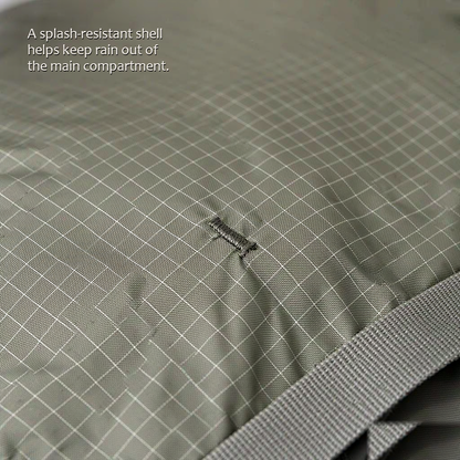 TrailFrame 75L hiking backpack in sage gray-green, close-up of the ripstop nylon shell with a bar-tack stitch point and a gray webbing strap in the corner.