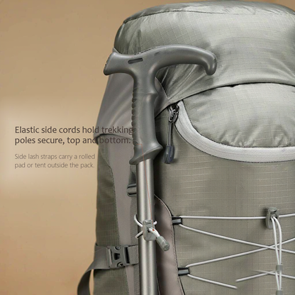TrailFrame 75L hiking backpack in sage gray-green, close-up of the side lash point where an elastic cord and webbing strap hold two matte aluminum trekking poles.